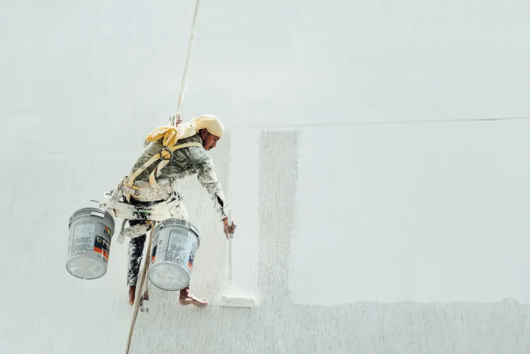 A painter cutting in a clean line against a white wall